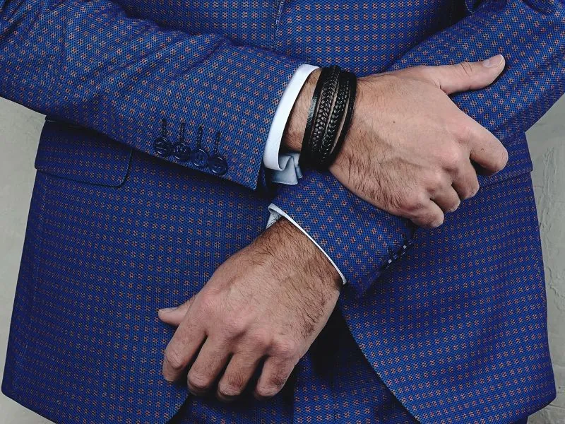 Detalhe de punho de terno azul com relógio e pulseira